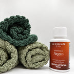 Argan next to towels 100ml bottle of scent booster on white background by aROMA Laundry 