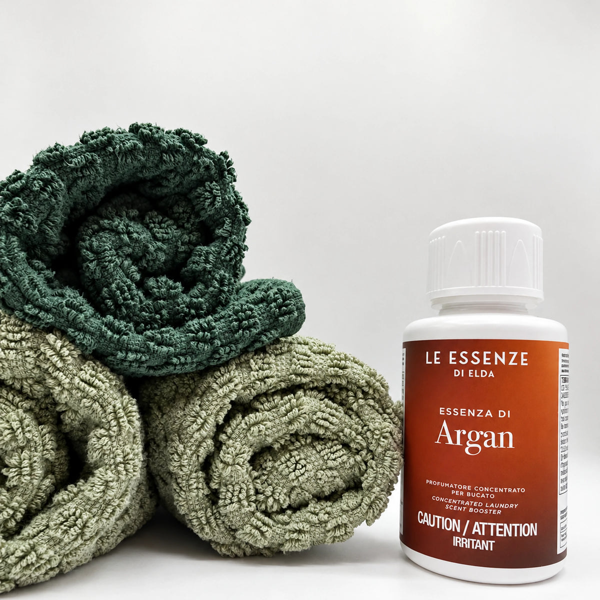 Argan next to towels 100ml bottle of scent booster on white background by aROMA Laundry 